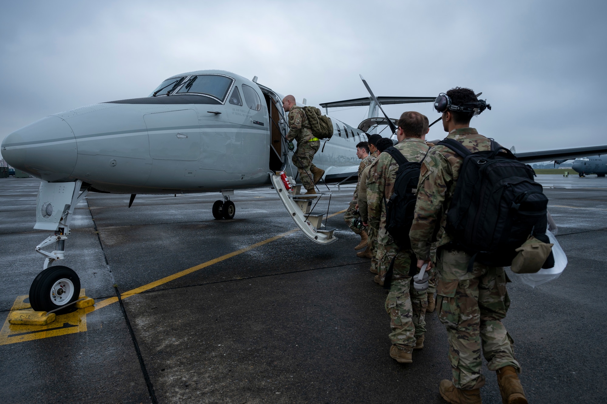 Military members form a line to board a C-12J aircraft.
