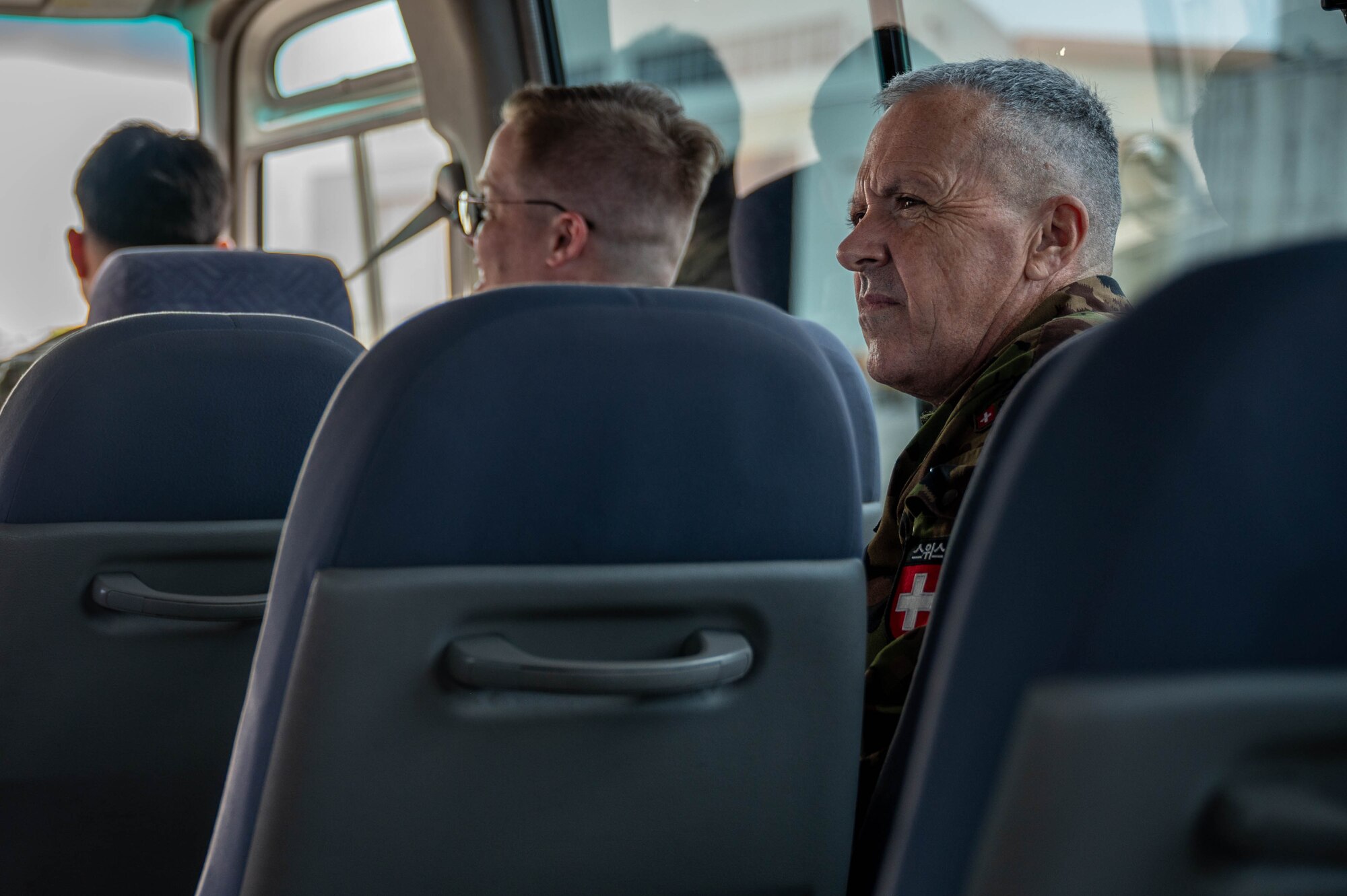 Swiss Army Member sits on a bus listening to a brief