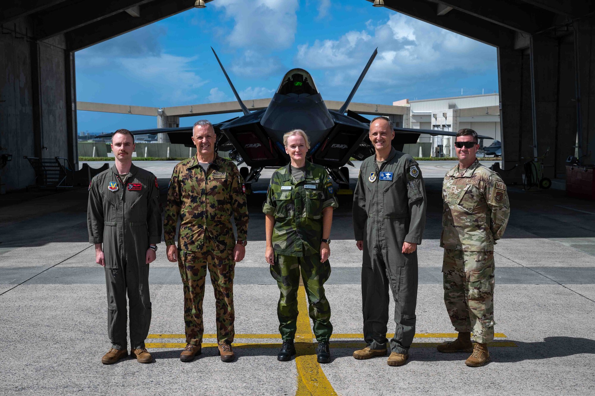 military members stand in front of a F-22A Raptor