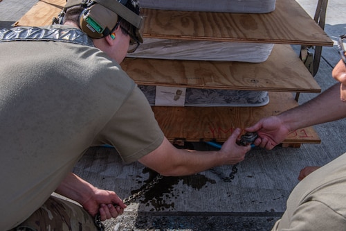 Airmen reaching for a chain on the ground