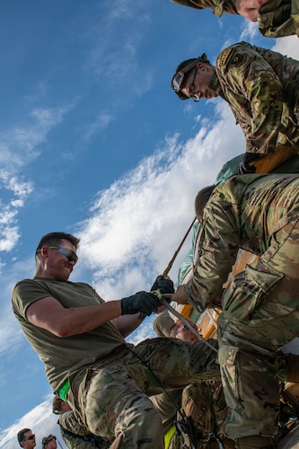 Airmen in the foreground strapping gear