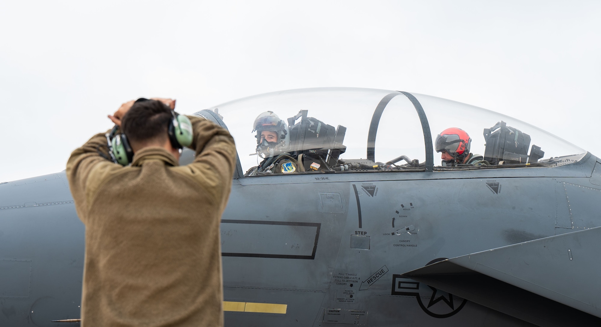Pilots look at U.S. Air Force maintainer as he gives them signals before a takeoff