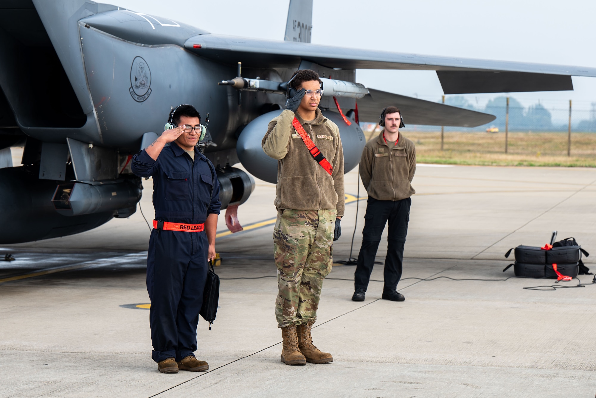 U.S. Airmen salute pilots in front of an F-15E Strike Eagle.
