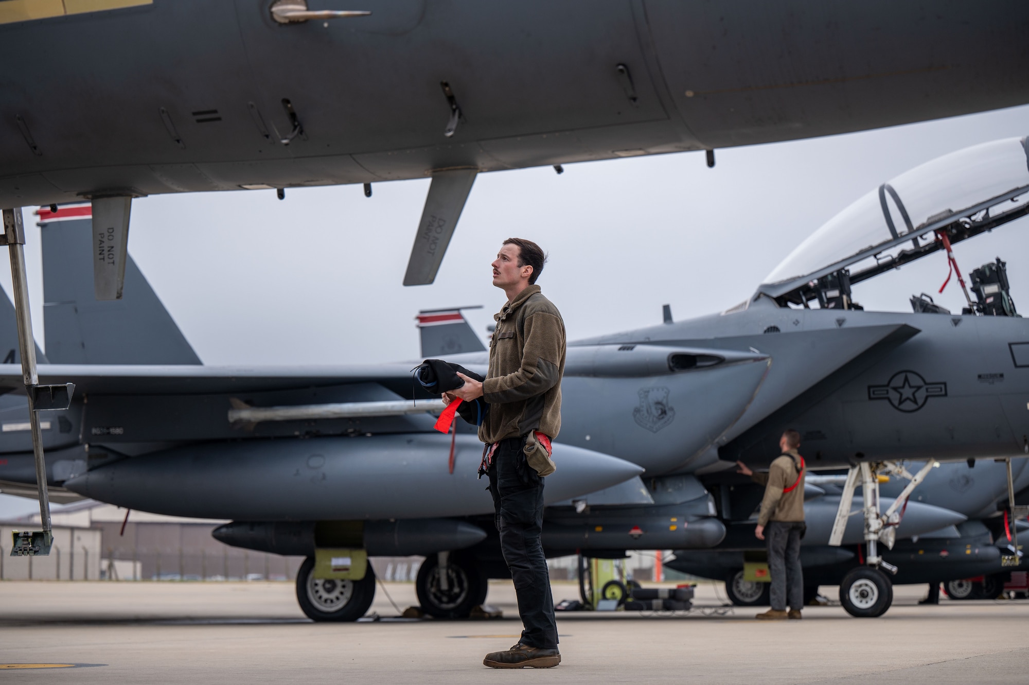 U.S. Air Force maintainer looks up at an F-15E Strike Eagle before pre-flight checks.