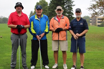 Four golfers stand on a golf course