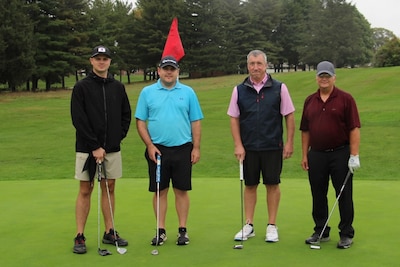 Four golfers stand on a golf course