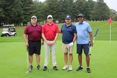 Four golfers stand on a golf course