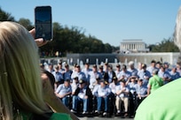A volunteer guardian from the Honor Flight Chicago takes a picture of the veteran group preceding a Joint Service Color Guard posting of the colors at the World War II Memorial in Washington, D.C., Oct. 23, 2024. The Joint Service Color Guard consists of National Capital Region service members from each branch of the U.S. military. (U.S. Air Force photo by Hayden Hallman)