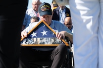Phil Collins, U.S. Navy Vietnam War veteran, bows his head during the invocation portion of a Joint Service Color Guard posting of the colors during Honor Flight Chicago’s Day of Honor at the World War II Memorial in Washington, D.C., Oct. 23, 2024. The Honor Flight Chicago presents photos of service members on an American flag, related to the veterans attending, who either passed away before Honor Flight Chicago was formed or killed in action. (U.S. Air Force photo by Hayden Hallman)