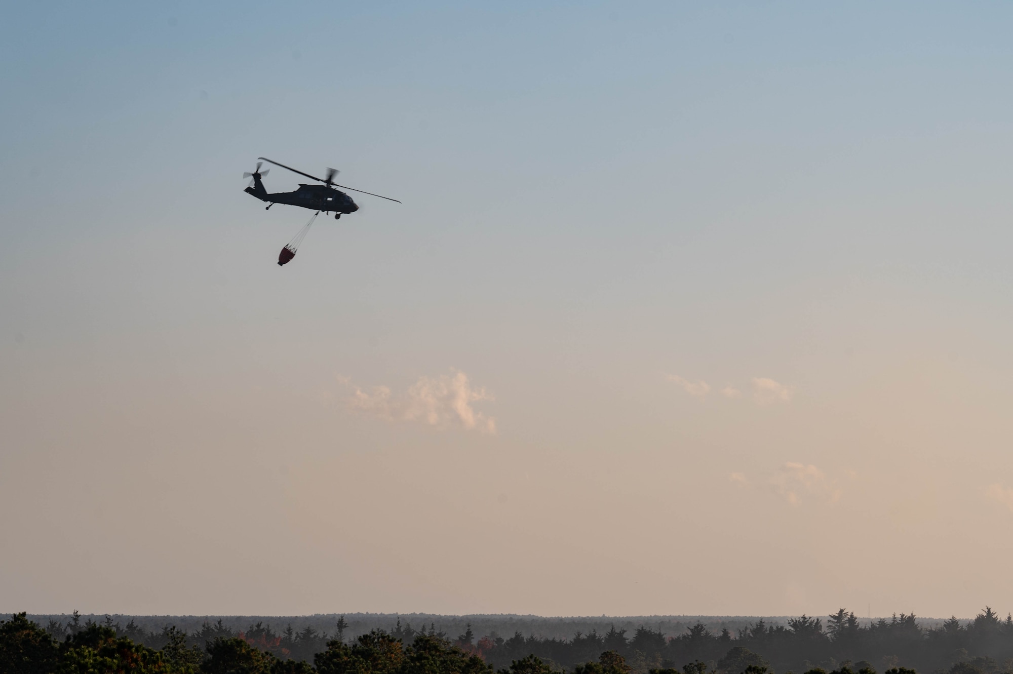 A UH-60 Black Hawk helicopter assigned to 1-150th Attack Helicopter Battalion, performs water drops over a controlled fire on the Joint Base McGuire-Dix-Lakehurst, N.J., range complex at JB MDL, Oct. 23, 2024. Our Joint Fire Fighters and Army partners utilized this training opportunity to promote inoperability, strengthening our capabilities through working together. (U.S. Air Force photo by Senior Airman Aidan Thompson)