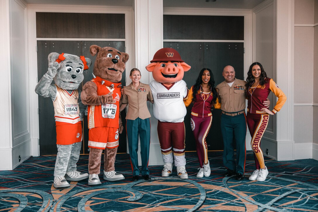 U.S. Marine Corps Col. Jenny Colegate, base commander, Marine Corps Base Quantico, and Sgt. Maj. Michael Brown, MCB Quantico sergeant major, pose for a photo with the Washington Commanders Command Force, and the Marine Corps Marathon mascots, during the opening ceremony of the 49th Marine Corps Marathon Health & Fitness Expo at the Gaylord National Resort and Convention Center in National Harbor, Maryland, Oct. 25, 2024. The MCM Health and Fitness Expo is the location for participants to pick up MCM race packets. The free expo welcomed participants, family members, friends, supporters, volunteers, and the general public to more than 100,000 square feet of exhibits and booths. (U.S. Marine Corps photo by Lance Cpl. Joaquin Dela Torre)