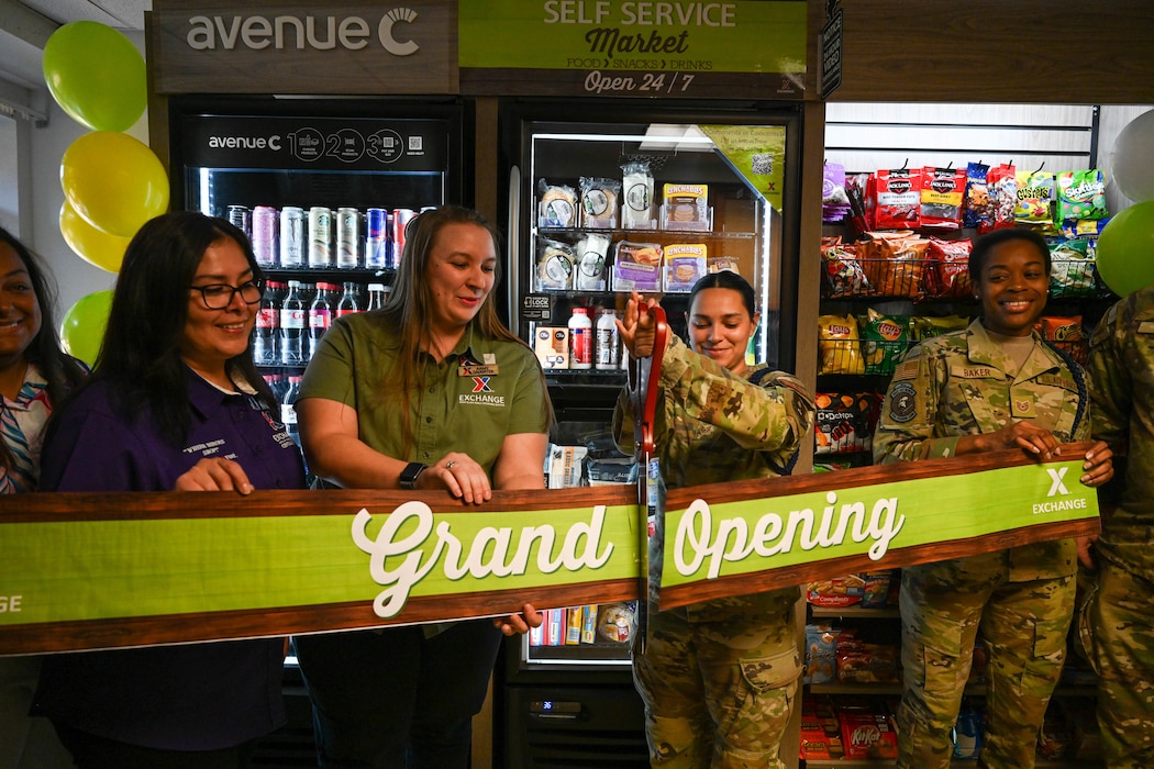 Women cut a grand opening sign.