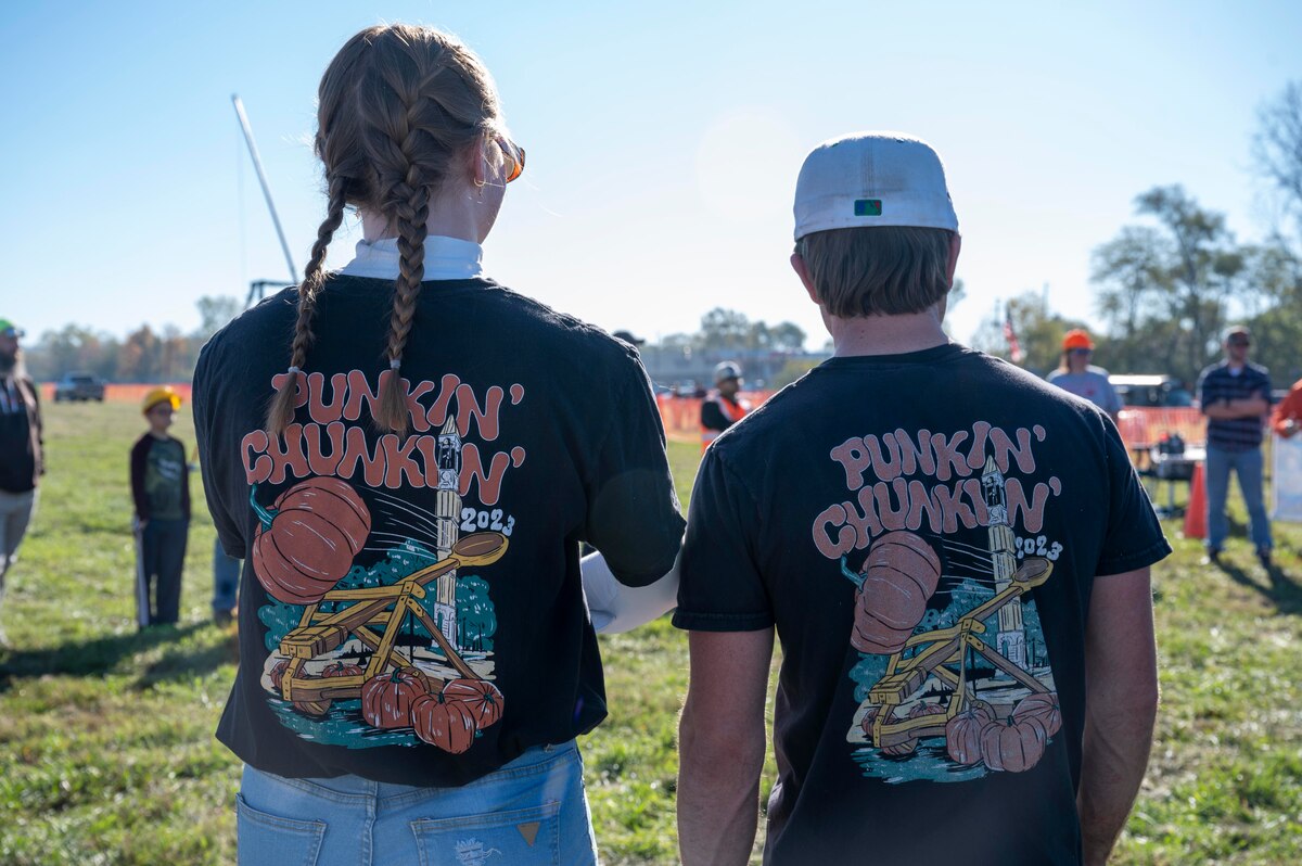 The backs of two people wearing shirts that say Pumpkin Chuck.