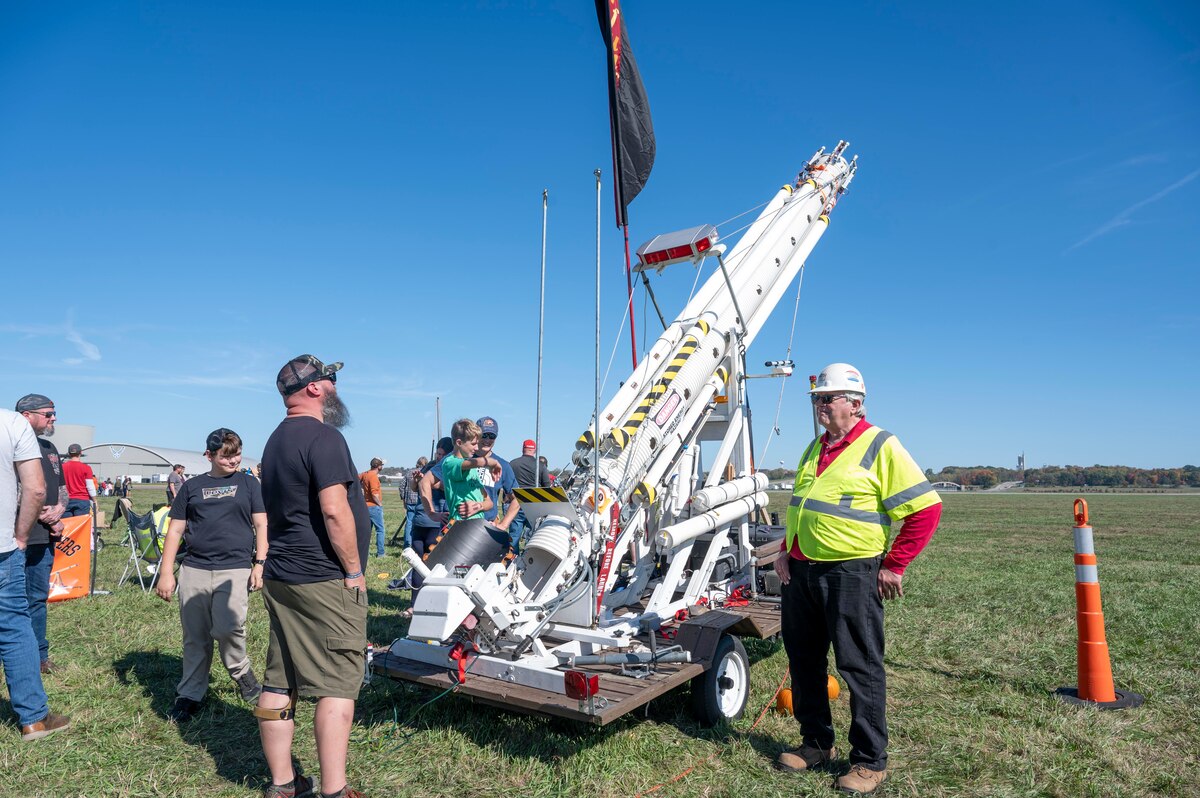 Several men looking at giant catapult.
