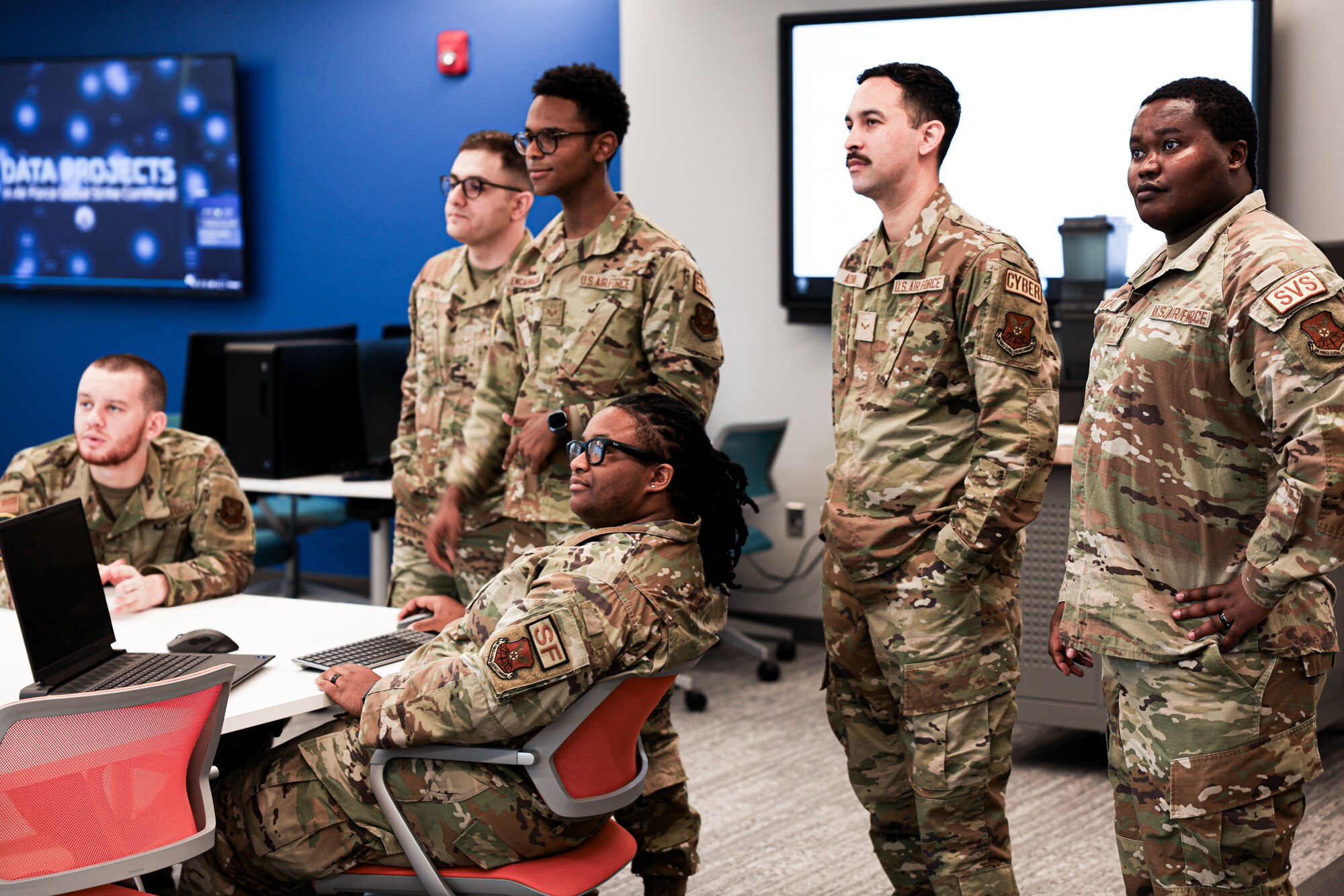 People are either standing or sitting around a desk