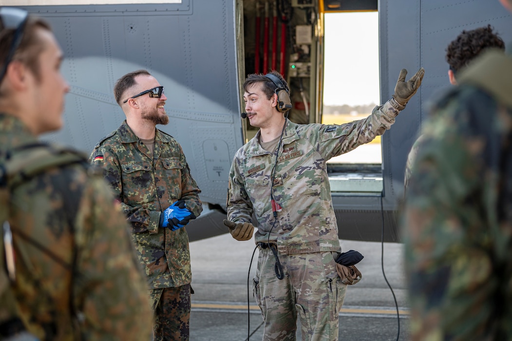 U.S. Air Force Staff Sgt. John Wheeler, 71st Rescue Squadron loadmaster, center, talks to a German military member at Moody Air Force Base, Georgia, Oct. 23, 2024. Wheeler was one of the instructors for Forward Area Refueling Point training done by Moody AFB Airmen to demonstrate the techniques to the visiting allies. (U.S. Air Force photo by Senior Airman Leonid Soubbotine)