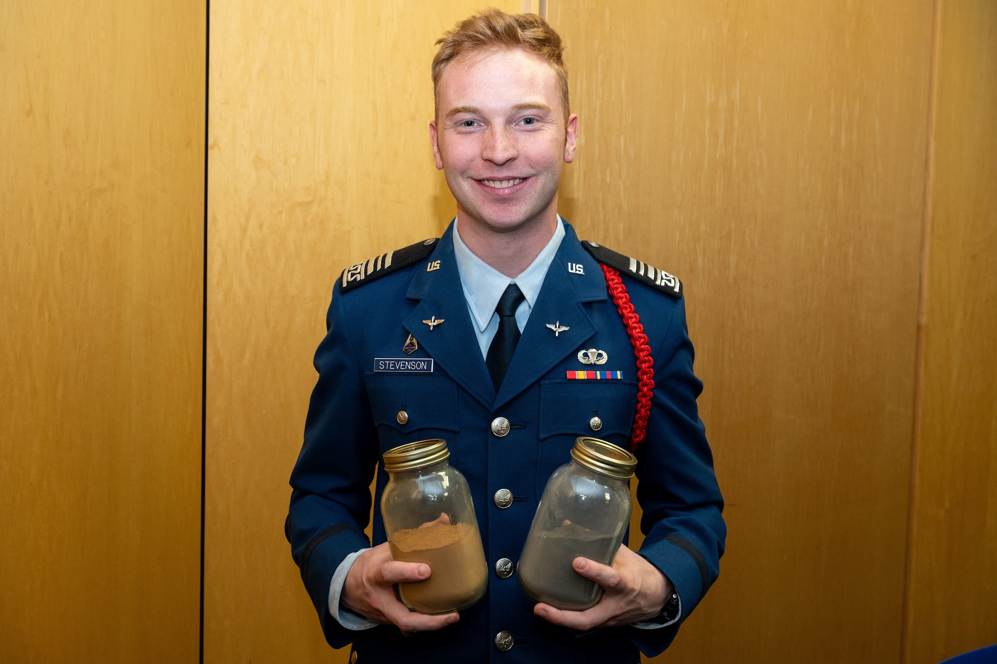 A cadet is pictured holding two jars. One jar contains lunar regolith simulant and the other jar contains martian regolith simulant during a civic leader tour at the U.S. Air Force Academy, Colorado on October 23rd 2024.