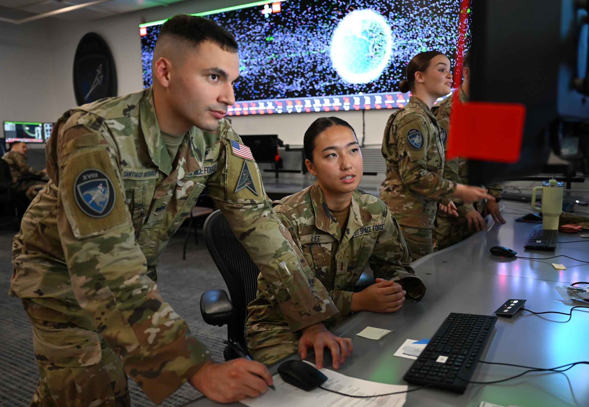 Two members in Space Force uniforms look at information on a computer screen.