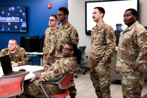 People are either standing or sitting around a desk