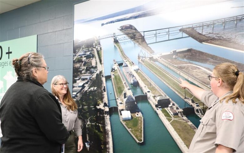 The U.S. Army Corps of Engineers, Detroit District Park Rangers Michelle Briggs and Melissa Martin point out where the New Lock at the Soo is being built to a visitor in the Soo Locks Visitor Center in Sault Ste. Marie, Michigan.