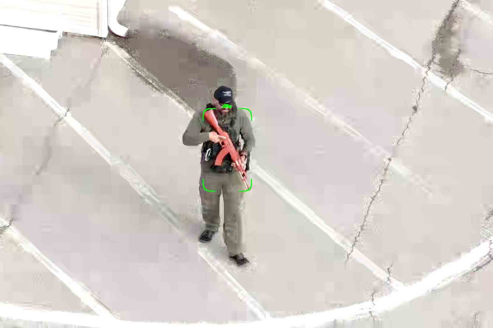 A man with an automatic rifle is highlighted by a recital on a display.