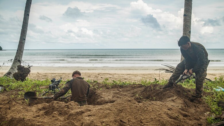 U.S. Marine Corps Cpl. Brandon Fix, left, and Lance Cpl. Nathan Grier, both machine gunners assigned to Weapons Company, Battalion Landing Team 1/5, 15th Marine Expeditionary Unit, dig a defensive position at a simulated costal defense site during exercise KAMANDAG 8 at Apurawan Beach, Palawan Province, Philippines, Oct. 20, 2024.