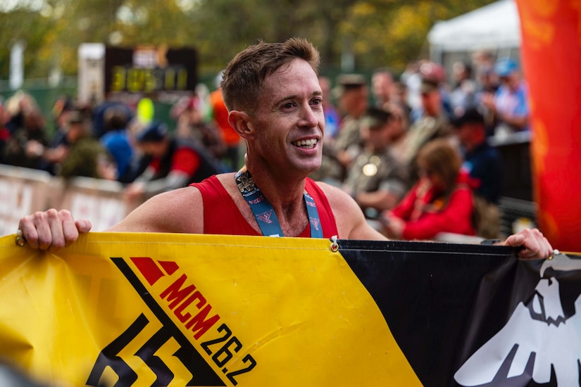 A runner smiles while holding a banner.