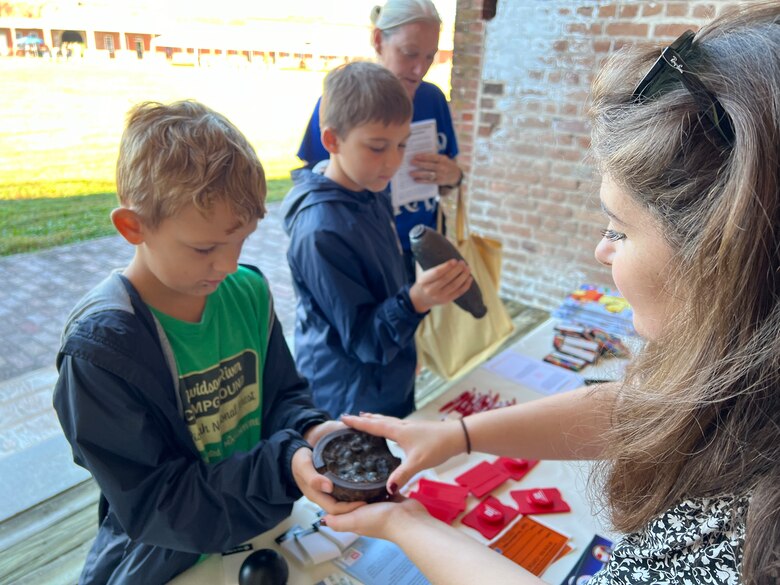 Madison Monroe, biologist, U.S. Army Corps of Engineers, Savannah District presents archeological artifacts recovered during District projects to visitors at Fort Pulaski during the national monument’s centennial celebration, in Savannah, Georgia, October 13, 2024. At the Corps’ booth, the volunteers answered questions and educated the public on the District’s mission.