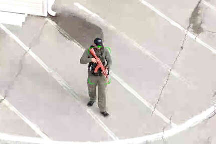 A man with an automatic rifle is highlighted by a recital on a display.
