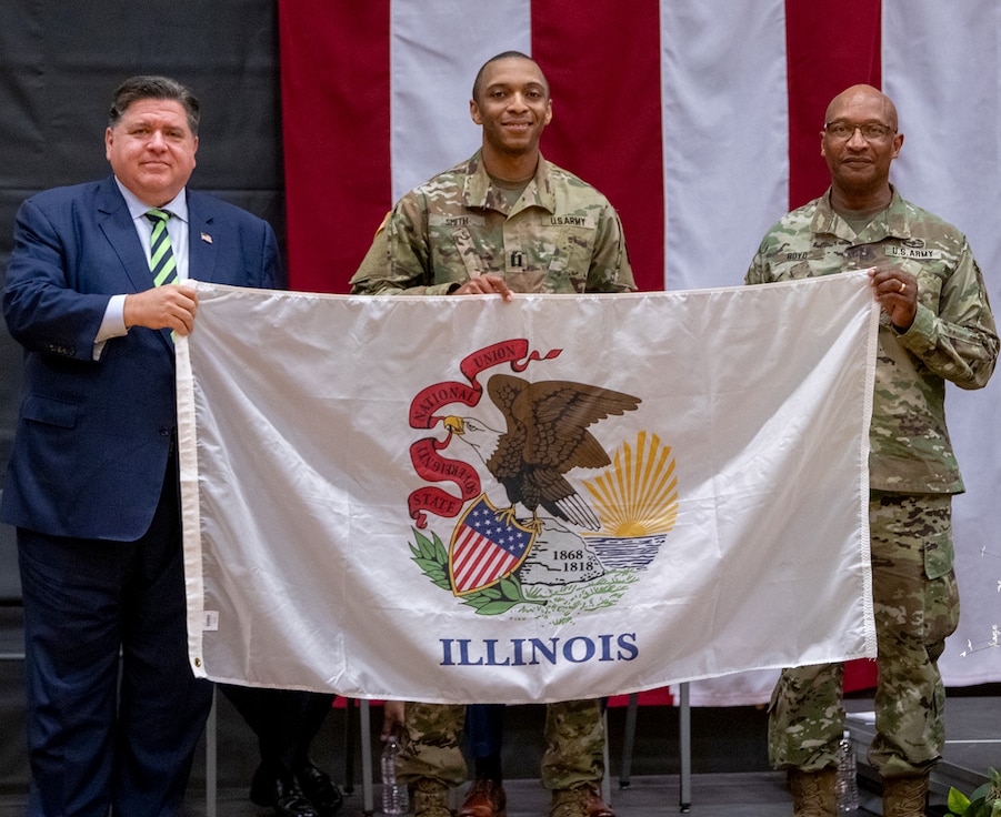 Gov. JB Pritzker and Maj. Gen. Rodney Boyd, The Adjutant General of Illinois and Commander of the Illinois National Guard, present a state of Illinois flag to Capt. Charles Smith III, Commander of the 725th Transportation Company to carry with them on their deployment to the U.S. European Command area of responsibility