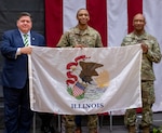 Gov. JB Pritzker and Maj. Gen. Rodney Boyd, The Adjutant General of Illinois and Commander of the Illinois National Guard, present a state of Illinois flag to Capt. Charles Smith III, Commander of the 725th Transportation Company to carry with them on their deployment to the U.S. European Command area of responsibility