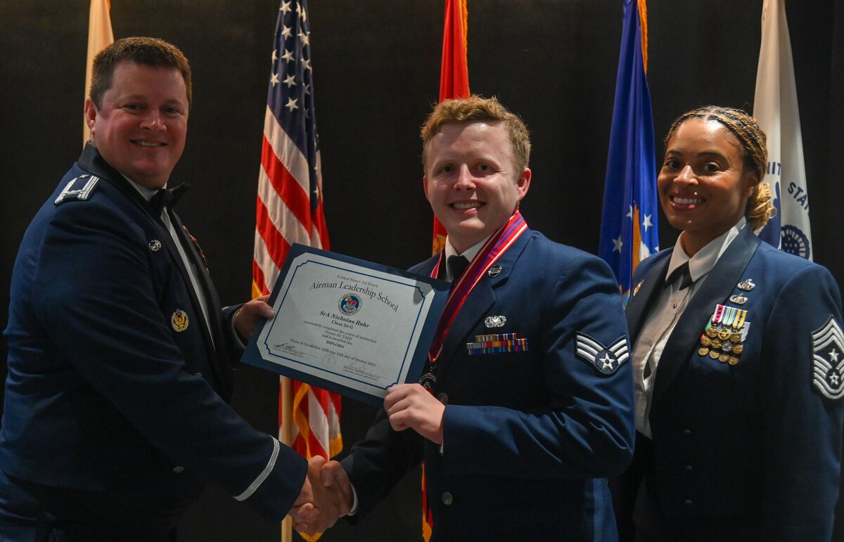 U.S. Air Force Col. Timothy Dalby, 17th Mission Support Group commander and Chief Master Sgt. Khamillia A. Washington, 17th Training Wing Command Chief present Senior Airman Nicholas Rohr, 47th Flying Training Wing, with the Airman Leadership School diploma at the Powell Event Center, Goodfellow Air Force Base, Texas, Oct. 24, 2024. ALS is a five-week course designed to prepare senior airmen to assume supervisory duties through instruction in leadership, followership and written and oral communication skills. (U.S. Air Force photo by Airman 1st Class James Salellas)