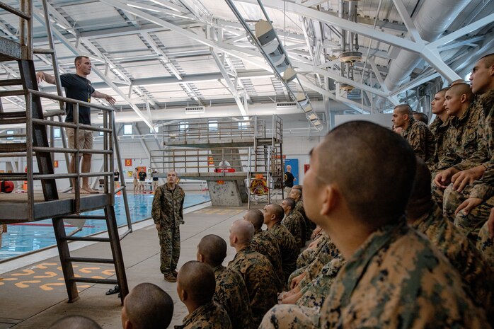U.S. Marine Corps Sgt. Darlye Jobe, a Marine Corps instructor of water survival, with Support Battalion, Recruit Training Regiment, gives a brief to recruits with Fox Company, 2nd Recruit Training Battalion, before they conduct a swim qualification event at Marine Corps Recruit Depot San Diego, California, Oct. 21, 2024. The basic swim qualification consists of a 25-meter swim, tower jump into the water, four-minute tread, 25-meter pack swim, and an underwater gear shed. (U.S. Marine Corps photo by Cpl. Sarah M. Grawcock)