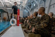 U.S. Marine Corps Staff Sgt. Brandon Gaddis, a Marine Corps instructor of water survival, with Support Battalion, Recruit Training Regiment, gives a brief to recruits with Fox Company, 2nd Recruit Training Battalion, during a swim qualification event at Marine Corps Recruit Depot San Diego, California, Oct. 21, 2024. The basic swim qualification consists of a 25-meter swim, tower jump into the water, four-minute tread, 25-meter pack swim, and an underwater gear shed. (U.S. Marine Corps photo by Cpl. Sarah M. Grawcock)