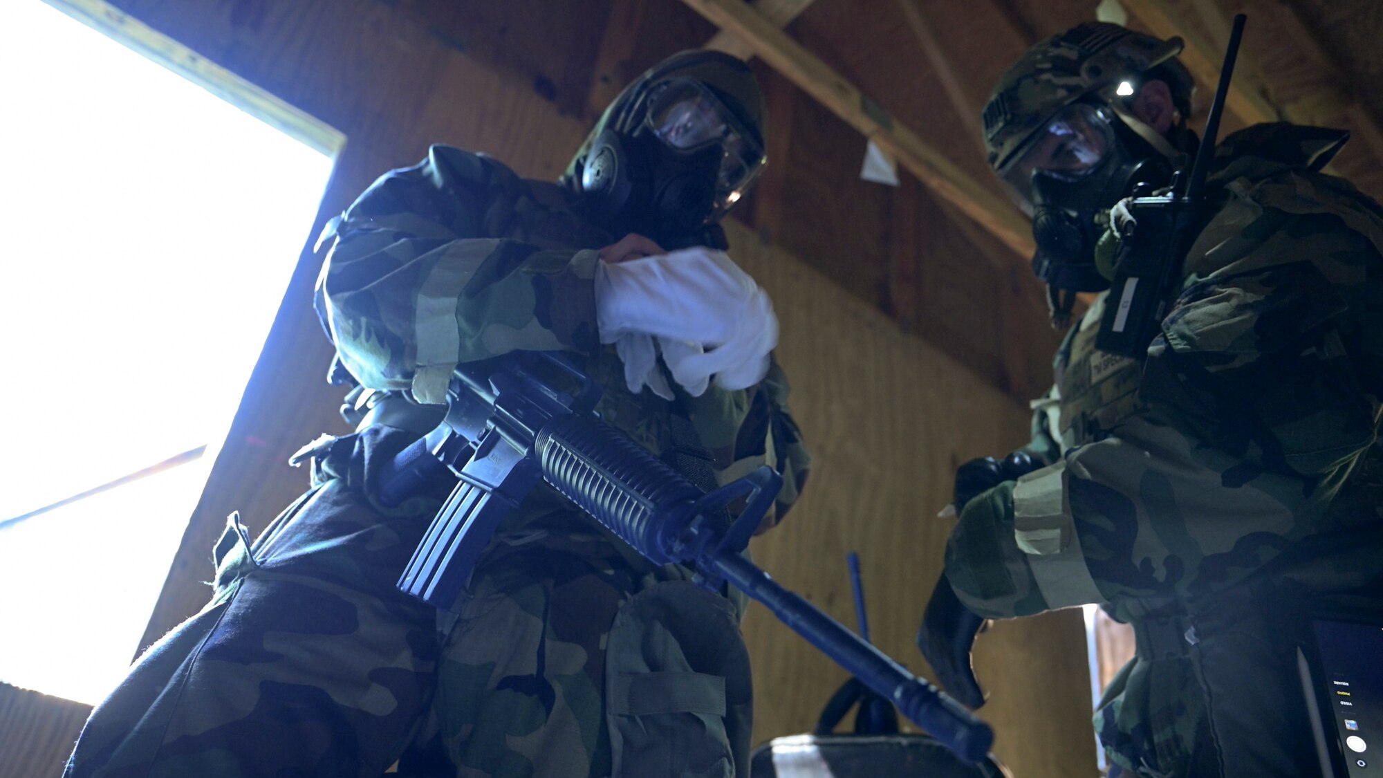 From left, U.S. Air Force Senior Airman Steven Fazakerley, training team member, and Senior Airman Samuel Baker, operations team member, both assigned to the 316th Civil Engineer Squadron, don protective gloves during a Chemical, Biological, Radiological, and Nuclear training exercise at Joint Base Andrews, Md., Aug. 23, 2024. The exercise involved full protective measures to simulate response conditions in hazardous environments. (U.S. Air Force photo by Staff Sgt. Isaac March)