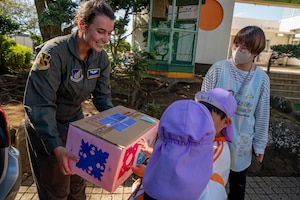 A service member receives a box of donations from a student.