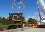 A large crane lifts the top portion of a locomotive off it's wheels.