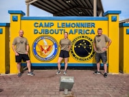 U.S. Air Force Lt. Col. Mathew Lehman, Staff Sgt. Jana Somero, and Senior Master Sgt. Stephen Berthiaume, all members of the 158th Fighter Wing, stand in front the sign for Camp Lemonnier