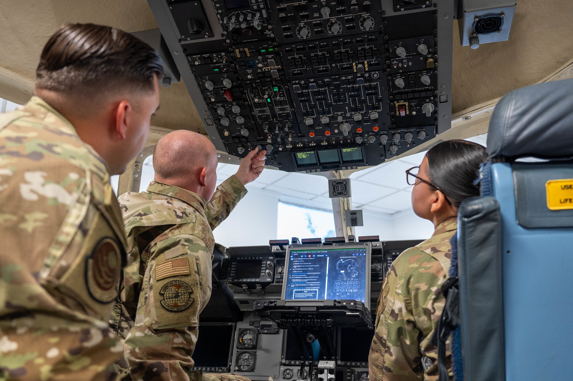 an instructor gives directions to two airmen inside a simulated C-17 Globemaster III cargo aircraft's flight deck