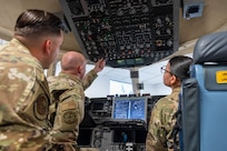an instructor gives directions to two airmen inside a simulated C-17 Globemaster III cargo aircraft's flight deck