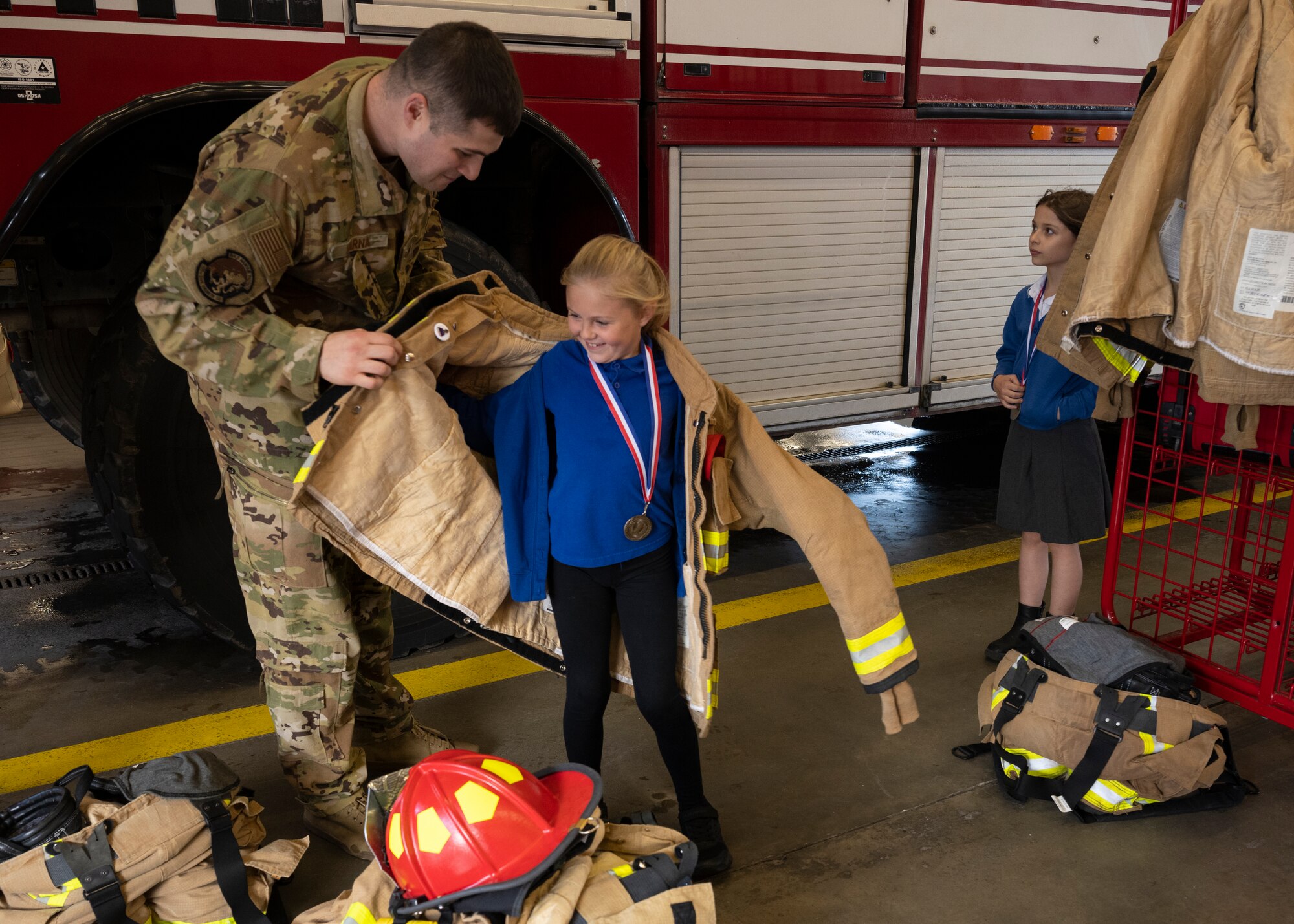 U.S. Air Force Staff Sgt. Zachary Barna, right, 100th Civil Engineer Squadron fire protection crew chief, helps a competition winner at Royal Air Force Mildenhall, England, Oct. 17, 2024.