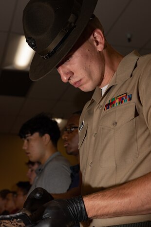 U.S. Marine Corps Sgt. Tanner N. Pond, a drill instructor with Receiving Company, Support Battalion, inspects recruits' belongings during Lima Company, 3rd Recruit Training Battalion’s, receiving event at Marine Corps Recruit Depot San Diego, Oct. 21, 2024. During the receiving process, recruits are checked for contraband, given haircuts, make scripted phone calls home, and are issued gear required for training. (U.S. Marine Corps photo by Lance Cpl. Janell B. Alvarez)