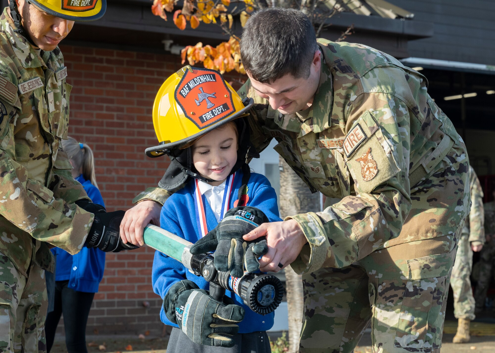 U.S. Air Force Staff Sgt. Zachary Barna, right, 100th Civil Engineer Squadron fire protection crew chief, helps a competition winner at Royal Air Force Mildenhall, England, Oct. 17, 2024.