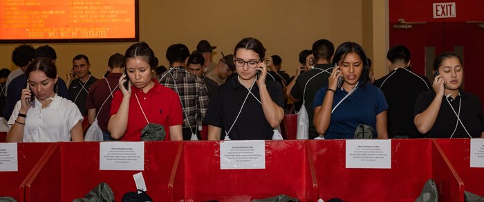 U.S. Marine Corps recruits with Lima Company, 3rd Recruit Training Battalion, make  scripted phone calls home during a receiving event at Marine Corps Recruit Depot San Diego, California, Oct. 21, 2024. During the receiving process, recruits are checked for contraband, given haircuts, make scripted phone calls home, and are issued gear required for training. (U.S. Marine Corps photo by Lance Cpl. Janell B. Alvarez)