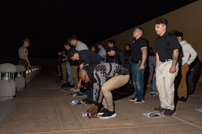 U.S. Marine Corps recruits with Lima Company, 3rd Recruit Training Battalion, pick up their personal items on the yellow footprints as part of a receiving event at Marine Corps Recruit Depot San Diego, California, Oct. 21, 2024. During the receiving process, recruits are checked for contraband, given haircuts, make scripted phone calls home, and are issued gear required for training. (U.S. Marine Corps photo by Lance Cpl. Janell B. Alvarez)
