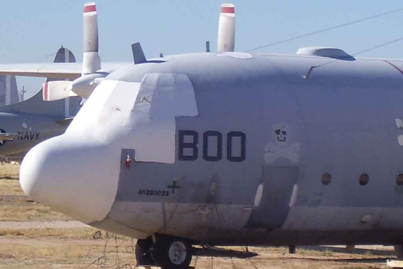 A defunct aircraft rests in the desert near other aircraft.