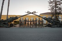 U.S. Marines with 11th Marine Regiment, 1st Marine Division, pose with Lance Cpl. Bruno, the mascot for Marine Corps Recruit Depot San Diego and Western Recruiting Region, under two M777 Howitzers at MCRD San Diego, California, Oct. 19, 2024. For the past 23 years, MCRD San Diego has hosted the Marine Corps Recruit Depot San Diego Boot Camp Challenge, a three-mile obstacle course race guided by 60 drill instructors that highlights the physical and mental demands of bootcamp. The event fosters comradery and community engagement through interaction with MCRD personnel. (U.S. Marine Corps photo by Cpl. Sarah M. Grawcock)
