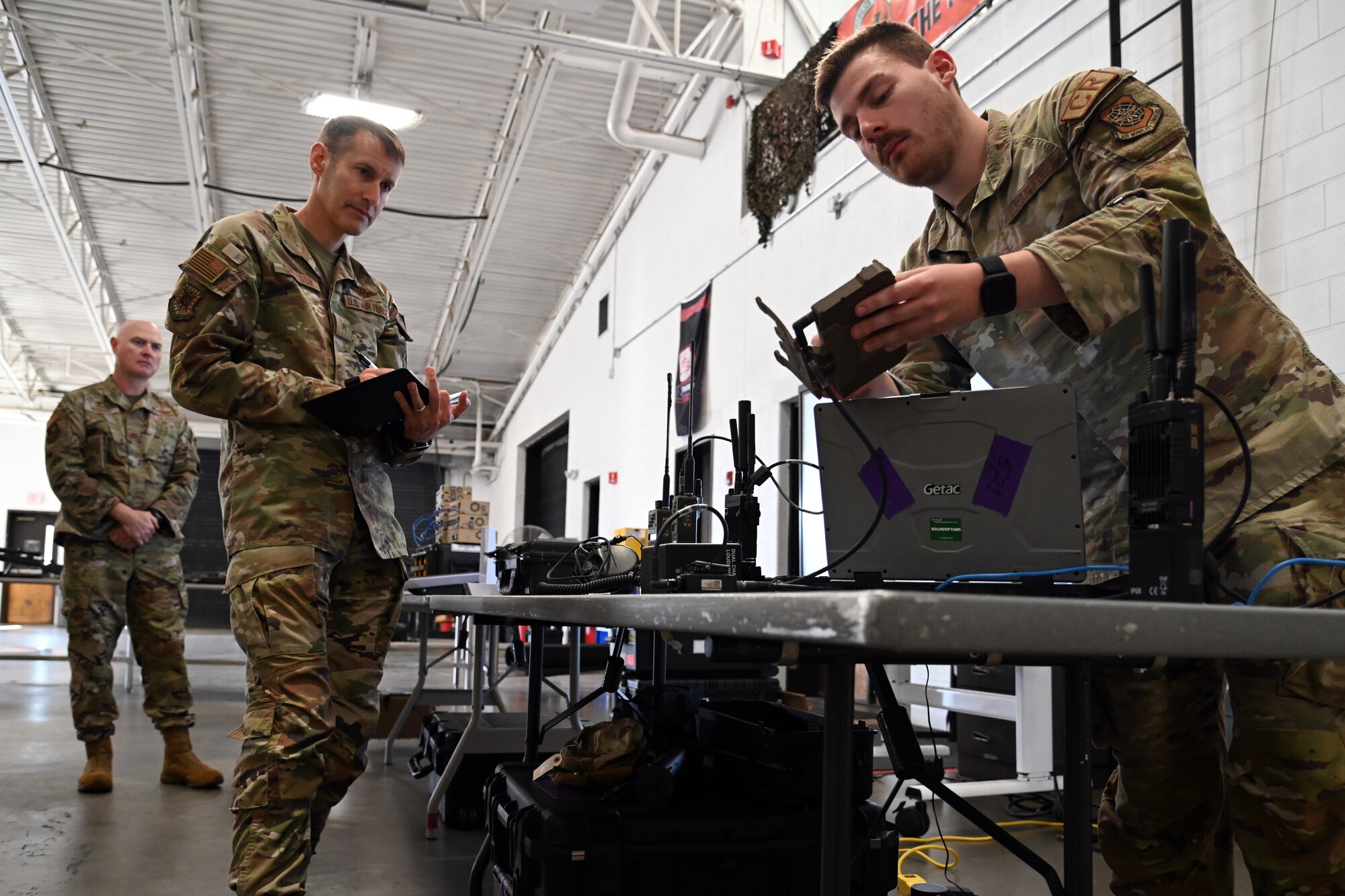 U.S. Air Force Brig. Gen. Stephen Snelson, U.S. Air Force Expeditionary Center commander, left, observes how U.S. Air Force Senior Airman Matthew Beard, 521st Contingency Response Wing communications specialist, right, operates the equipment the wing uses during exercises and real-world missions during an immersion demonstration, Oct. 7, 2024, at Joint Base McGuire-Dix-Lakehurst, New Jersey. The command team visited multiple contingency response squadrons to observe how the Airmen align with Air Force priorities to prepare and respond to the fight of tomorrow.