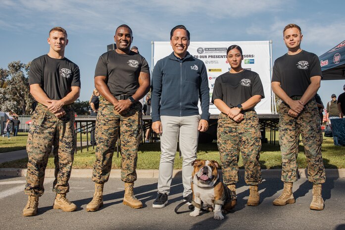 Todd Gloria, mayor of the city of San Diego, poses for a photo with U.S. Marine Corps Lance Cpl. Bruno, the  Marine Corps Recruit Depot San Diego and Western Recruiting Region mascot, and Marines with MCRD San Diego during the 2024 Marine Corps Recruit Depot San Diego Boot Camp Challenge at MCRD San Diego, California, Oct. 19, 2024. For the past 23 years, MCRD San Diego has hosted the Boot Camp Challenge, a three-mile obstacle course race guided by 60 drill instructors that highlights the physical and mental demands of bootcamp. The event fosters comradery and community engagement through interaction with MCRD personnel. (U.S. Marine Corps photo by Cpl. Sarah M. Grawcock)