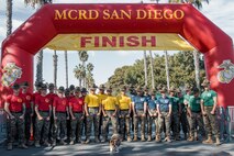 U.S. Marine Corps drill instructors with Recruit Training Regiment, pose for a photo with Lance Cpl. Bruno, the  Marine Corps Recruit Depot San Diego and Western Recruiting Region mascot, at the finish line during the 2024 Marine Corps Recruit Depot San Diego Boot Camp Challenge at MCRD San Diego, California, Oct. 19, 2024. For the past 23 years, MCRD San Diego has hosted the Boot Camp Challenge, a three-mile obstacle course race guided by 60 drill instructors that highlights the physical and mental demands of bootcamp. The event fosters comradery and community engagement through interaction with MCRD personnel. (U.S. Marine Corps photo by Cpl. Sarah M. Grawcock)